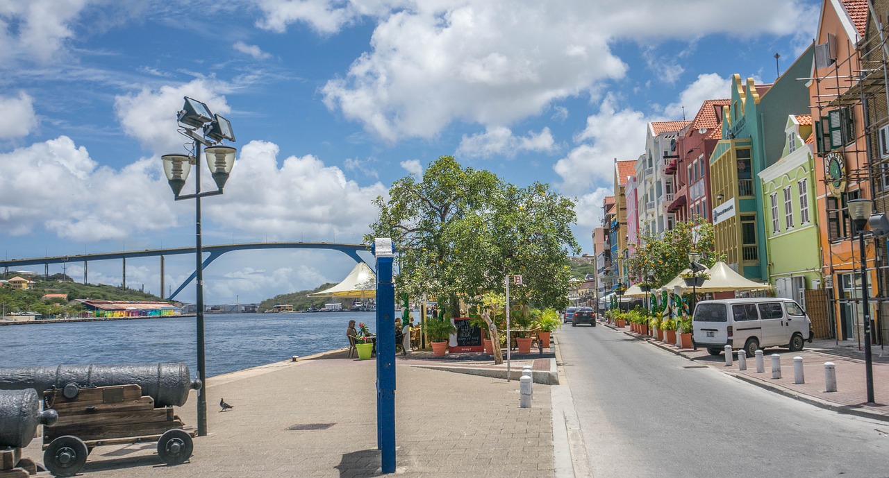 Colorful facades and sidewalk cafes lining the street and harbour in Curacao.